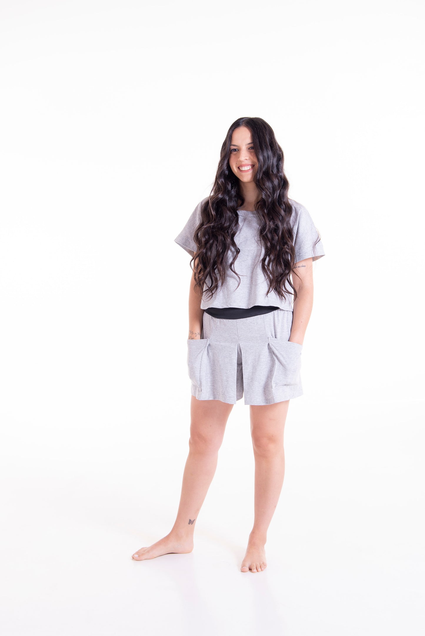 Woman wearing a light gray outfit with shorts and a top on a white background