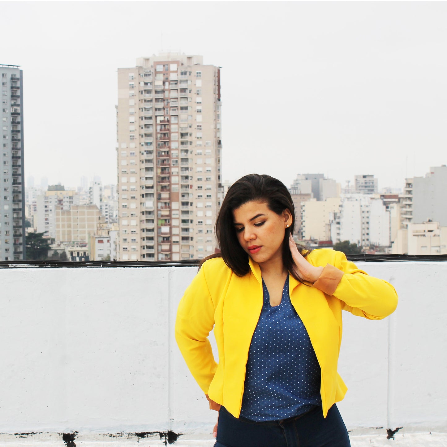 Woman in a yellow Camellia jacket standing on a rooftop with cityscape in the background