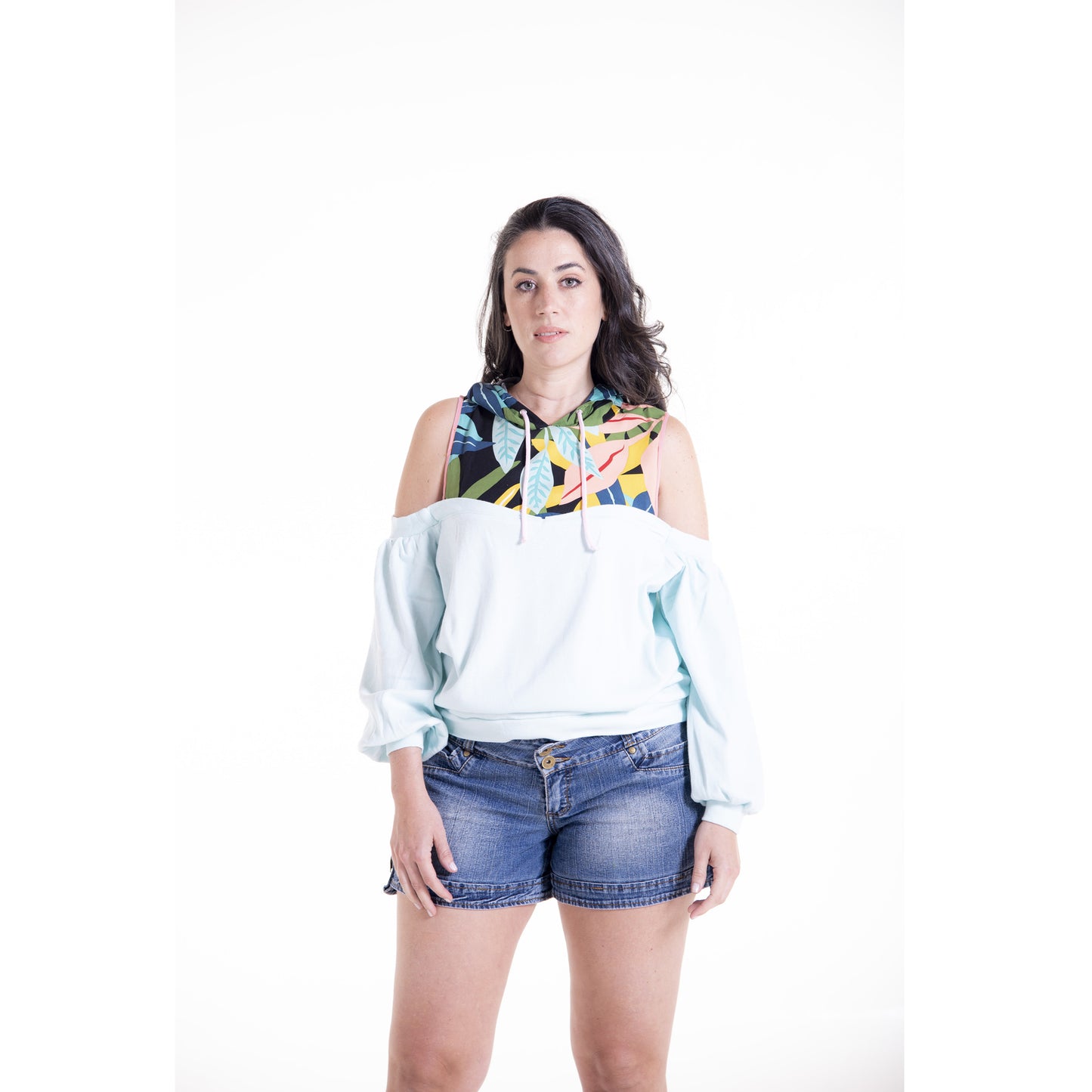 Woman wearing a colorful hoodie and denim shorts on a white background