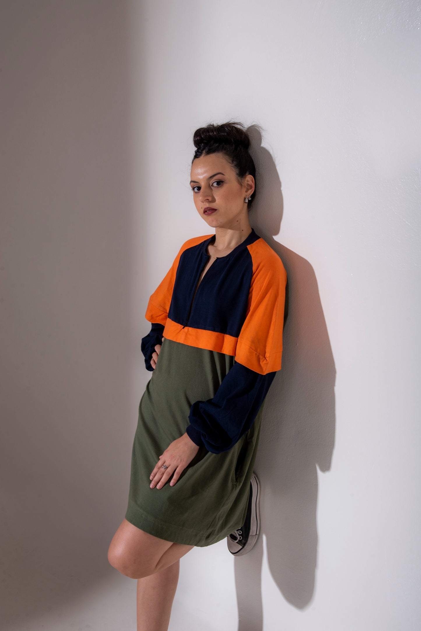 Woman wearing a colorful Dahlia raglan dress against a white wall - outfit inspiration