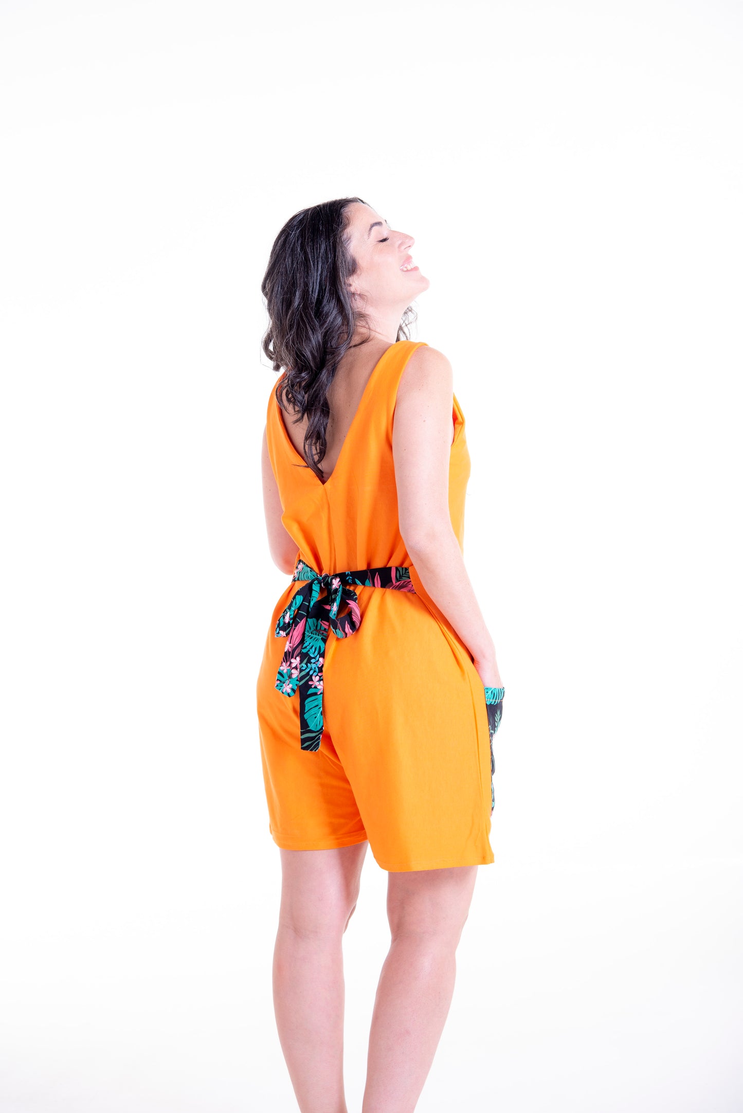Side view of orange Wisteria wrap jumpsuit short version with pocket details